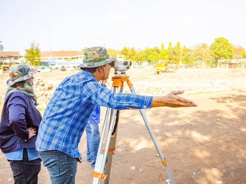 Land surveyor measuring a property boundary to help prevent fence disputes and encroachment issues